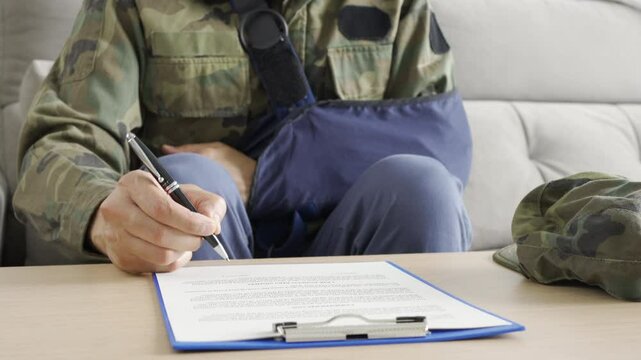 Front view of a disability soldier with sling signing contract at office