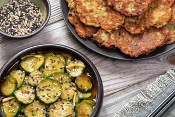 Zucchini and chickpea flour pancakes, sliced cucumbers pickled in soy sauce, and black and white sesame seeds. Vegan snack or lunch.