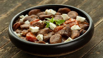 Ful Mudammas (Medammes) in bowl on wooden rustic table. Egyptian dish made of dried fava bean, onion, garlic, tomatoes, and olive oil, often served as a sandwich filler. 