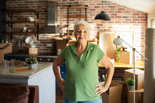 Portrait of senior confident woman in apartment filled with moving boxes
