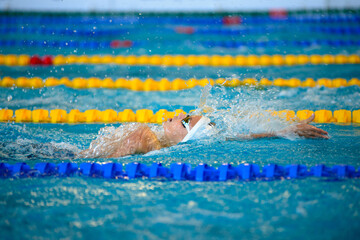Swimmer boy swims backstroke swimming style in the pool