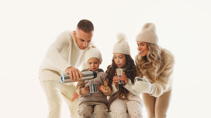 Dad pours hot tea while kids eagerly hold their mugs, savoring sweet family moment on ice against...