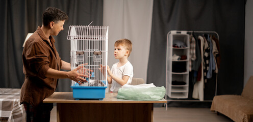 Small family at mother and her little son taking care of a pet rabbit in its habitat, fostering responsibility and pet care skills in cozy home setting.