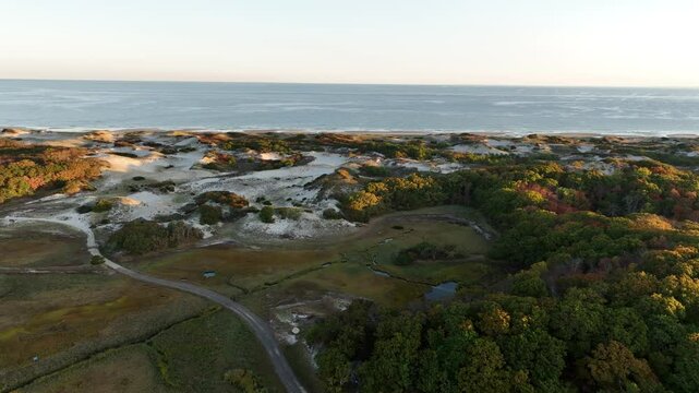 Cape cod's sand dunes and salt marsh at sunrise with ocean in the distance, aerial view