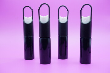 mini sprayer bottles isolated on purple background. four sprayer bottles with hangers