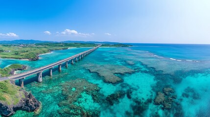 Obraz premium An aerial view of a long bridge connecting two islands over a turquoise ocean. The bridge is surrounded by crystal clear water and vibrant coral reefs.