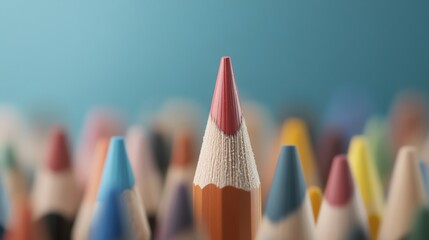 Close-up of a vibrant colored pencil standing out among others against a blue background, symbolizing creativity and individuality.
