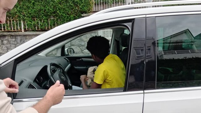 A smiling delivery man hands a paper bag to a customer from his car window. Concept of efficient car delivery service.