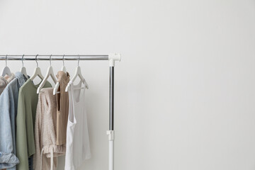 Rack with clothes near white wall. Space for text