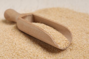 Pile of oat bran and wooden scoop on table, closeup