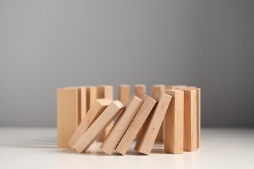 Domino effect. Wooden blocks falling on white table