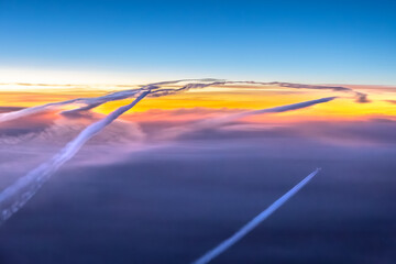 Aerial cockpit pilot view of aircraft, plane contrails, vapour cloud in pink landscape in air above...