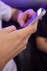 Obraz premium A person is using a smartphone in a social environment where others are also present