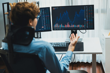 Young investor stock trader calling on smartphone to broker, discussing with dynamic financial exchange investment on two laptop screens in current market graph in real time at modern office. Gusher.