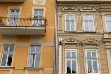 Obraz premium There is a bright yellow building complete with a charming balcony situated right next to a neighboring brown building that adds contrast