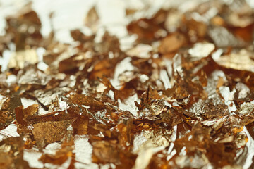 Yellow gold leaf flakes on the golden metallic background. Close up macro