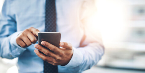 All it takes is the right contact. Cropped shot of an unrecognizable businessman using his phone in the office.