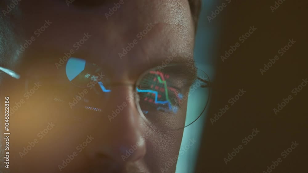 Poster trader wearing glasses is working on laptop computer. screen with stock market charts and bitcoin bt