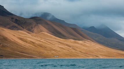 Serene waters and rugged mountains of Svalbard under cloudy skies in late summer