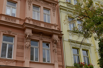 There is a pink and yellow colored building that stands prominently, with a beautiful tree located right in front of it, creating an attractive view