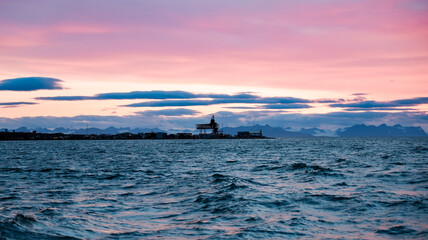 Sunset over the serene waters of Svalbard with distant mountains and a fishing platform