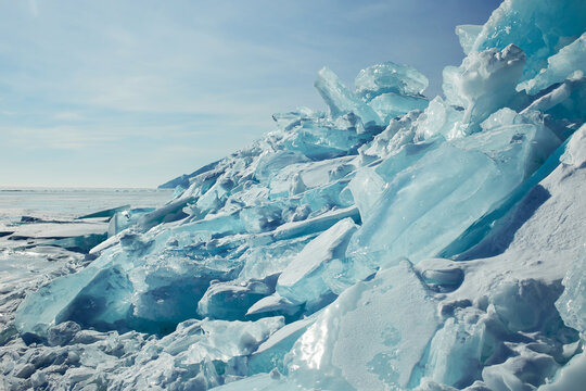 Winter landscape. Huge blocks of transparent blue ice covered with snow, hummocks on the frozen Lake 