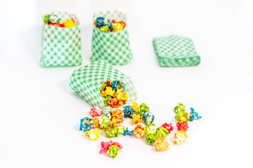 Colorful popcorn in focus, with blurred bags in the background. Focus is on the spilled popcorn, perfect for themed events and decorations.
