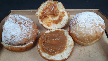 Donuts with jam in a cardboard box on a black background.