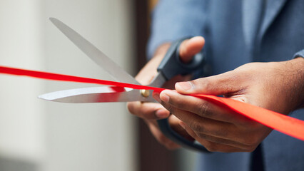 Close-up of scissors cutting red ribbon a grand opening event, symbolizing start of new business...