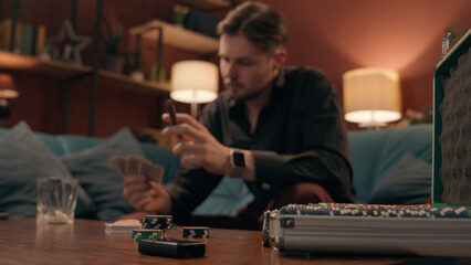 Unlucky sad frustrated Caucasian man male guy player gambler playing poker cards lost game blackjack defeat competition upset stressed gamer smoking cigar betting losing wager gambling addiction home