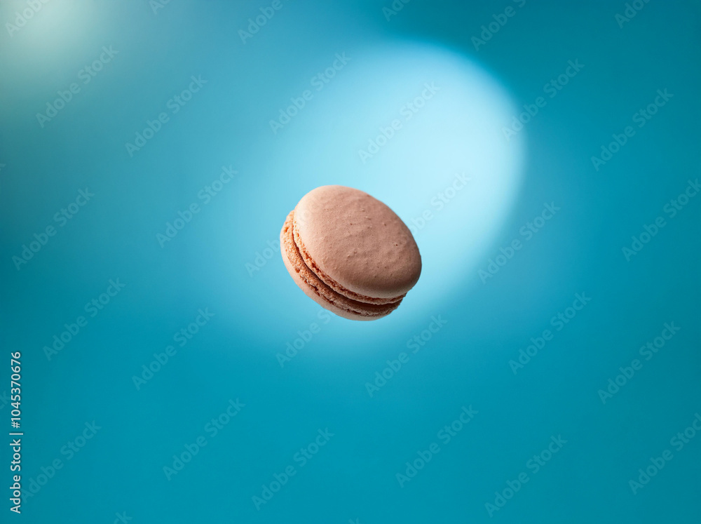 Poster a single pink macaron is floating in midair against a blue background.