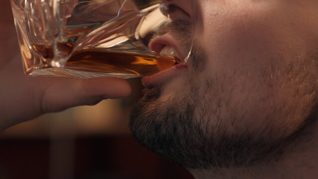 Close up happy laughing Caucasian drunk addict man male bearded businessman guy client customer drinking glass expensive alcohol liquor whiskey at home room. Alcoholism addiction unhealthy lifestyle