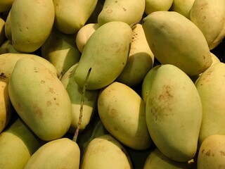A Pile of Fresh Mangoes in a Basket for Sale at a Local Market, highlighting their ripeness, smooth texture, and natural appeal.