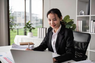 Young Female Accountant Working Diligently on Paperwork in a Modern Office Setting with Natural Light