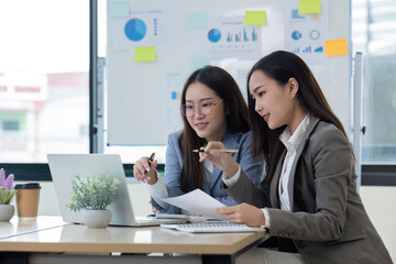 Two Female Accountant Collaborating on Financial Graphs and Data Analysis in a Modern Office Setting