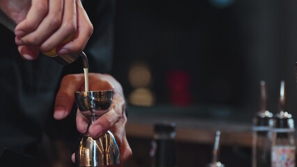 Closeup mixing hand bartender holding jigger to measure juice into shaker design preparation for mixed cocktail at bar. Special refresh drink showcasing nightlife mixology inviting at club. Vinosity.