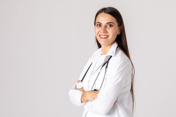 Portrait of beautiful female doctor in white coat while standing with crossed arms on white...