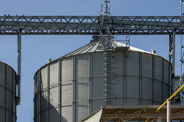 The tall and metallic steel grain silos are essential components of agricultural infrastructure under a clear blue sky