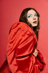 A young woman showcases her beauty in a stunning red ensemble, surrounded by vibrant colors.