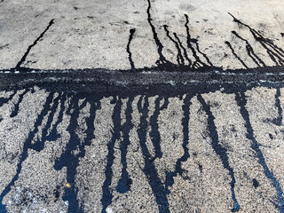 Asphalt on road. Street with black tar filling the cracks. Cracks in concrete surface are then...