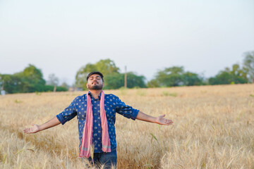 Young Indian smart farmer standing in wheat farm