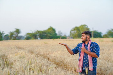 Young Indian smart farmer standing in wheat farm