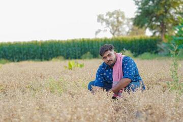 Young Indian smart farmer standing in wheat farm