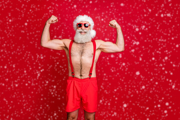 Portrait of nice attractive content cheerful funky glad content strong powerful cool gray-haired strong man trainer instructor bodybuilder showing muscles isolated on bright vivid shine red background