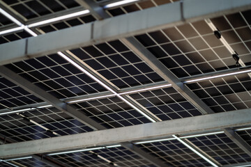 A solar panel is installed on the ceiling of a building. The panels are black and white and are arranged in a grid pattern. The panels are illuminated by lights