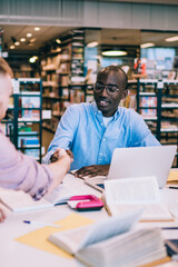 Multiethnic students shaking hands in library