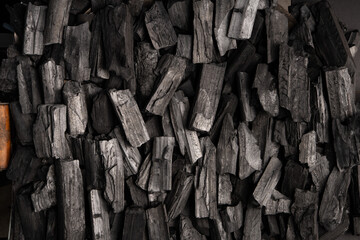 New, black coals, arranged in a neat bed, without embers. The pieces are lined up, ready to light, with a rough texture and dark hue