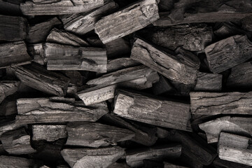 New, black coals, arranged in a neat bed, without embers. The pieces are lined up, ready to light, with a rough texture and dark hue