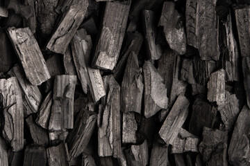 New, black coals, arranged in a neat bed, without embers. The pieces are lined up, ready to light, with a rough texture and dark hue