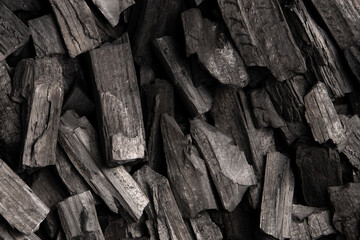 New, black coals, arranged in a neat bed, without embers. The pieces are lined up, ready to light, with a rough texture and dark hue